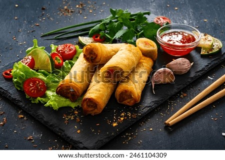 Spring rolls filled with cooked vegetables served with sauces on wooden table 