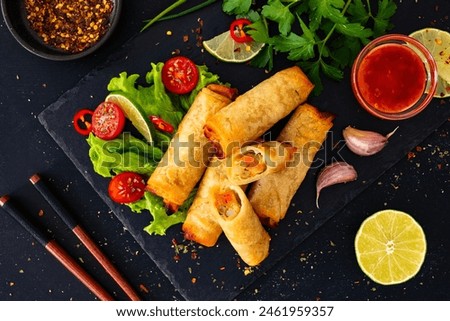 Spring rolls filled with cooked vegetables served with sauces on wooden table 