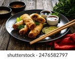 Spring rolls and sauces on wooden table 