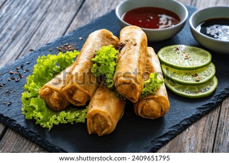 Spring rolls and sauces on wooden table