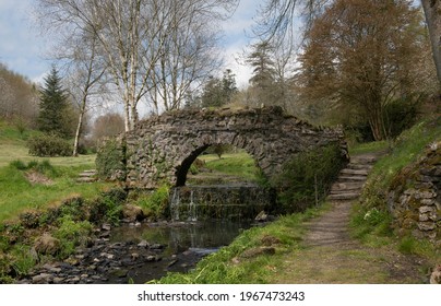 Spring Rustic Landscape of an Old Stone Foot Bridge Crossing a Stream in Rural Devon, England, UK