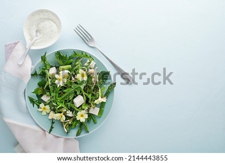 Spring salad with dandelion, asparagus, flowers, nettle and cream cheese. Healthy spring detox food ingredients.