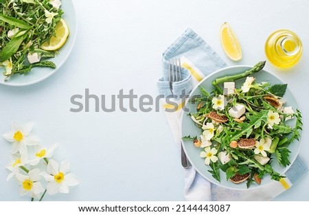 Spring salad with dandelion, asparagus, wild garlic, flowers, nettle and cream cheese. Healthy spring detox food background.