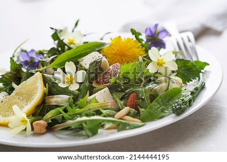 Spring salad with dandelion, asparagus, wild garlic, flowers, nettle and cream cheese. Healthy spring detox food ingredients. 