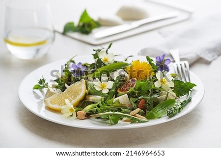 Spring salad with dandelion, asparagus, wild garlic, flowers, nettle and cream cheese. Healthy spring detox food ingredients.