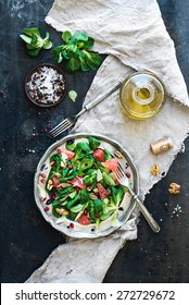 Spring salad with lamb's lettuce, grapefruit, garnet, walnuts and olive oil in vintage metal plate over dark grunge backdrop, top view