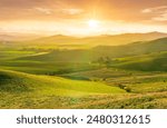 spring season green landscape of green field and meadow in a hill countryside with mountains and beautiful sunset sky on background