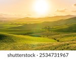 spring season green landscape of green field and meadow in a hill countryside with mountains and beautiful sunset sky on background