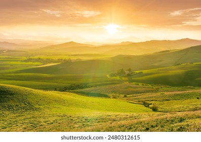 spring season green landscape of green field and meadow in a hill countryside with mountains and beautiful sunset sky on background - Powered by Shutterstock