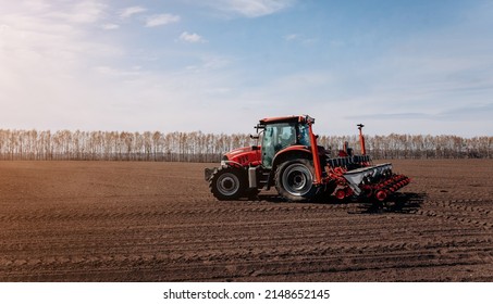 Spring sowing season. Farmer with a tractor sows corn seeds on his field. Planting corn with trailed planter. Farming seeding. The concept of agriculture and agricultural machinery. - Shutterstock ID 2148652145