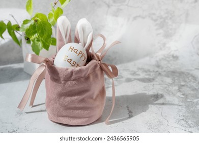 Spring still life with colored eggs. Easter bunny and eggs with a delicate color pattern in a nest. Easter decor in the house in a low key. Close-up.
