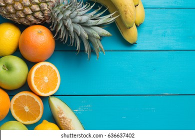 Spring or Summer concept : Many kinds of fruit lying on colorful wooden table, can use for summer or food content background. Orange, apple, banana, melon, pineapple on blue wooden table.