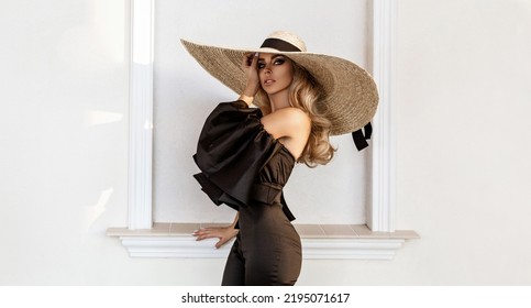 Spring, Summer Fashion. High Fashion Model. Glamour, Stylish Elegant Woman In Black Jumpsuit And Big Hat. Female Model In Stylish Look In The City. Travel Model. Outdoor Shoot. Vogue. Elegance.