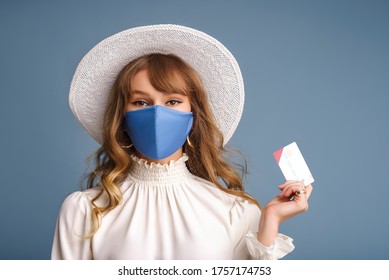 Spring, Summer Online Shopping During Quarantine Conception: Fashionable Woman Wearing Protective Mask Posing With Plastic Bank Card. Blue Background
