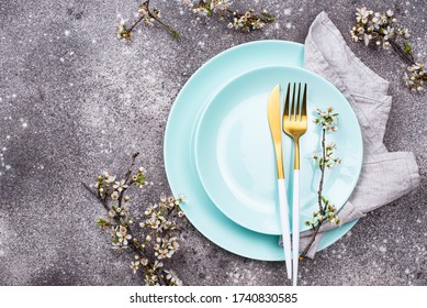 Spring table setting with blooming branch and trendy aqua menthe color plate