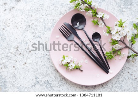 Spring table setting with white cherry blossom and cutlery on grey background. Mockup design layout for your text. Mothers Day concept. Copy space. Top view. Flat lay.