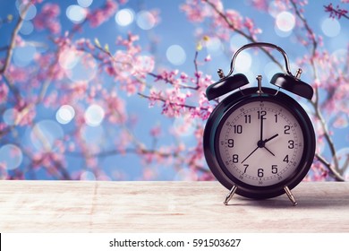 Spring Time Change Concept With Alarm Clock Over Nature Tree Blossom Background