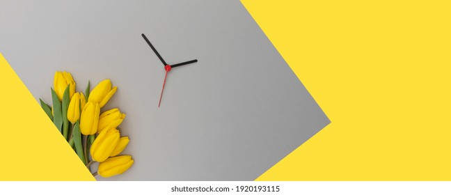 Spring Time Change Concept. 
Yellow Tulips And Clock Hands On A 2021 Color Backdrop.