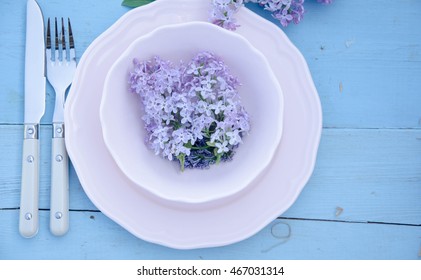 Spring time table setting with lilac flowers and vintage plates
