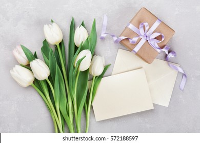 Spring tulip flowers, gift box and paper card on gray stone table from above in flat lay style. Greeting for Womens or Mothers Day. - Powered by Shutterstock