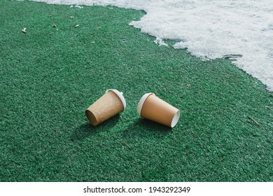 In the spring, two empty coffee cups were thrown onto a green plastic floor in a park. Environmental pollution with household waste.
