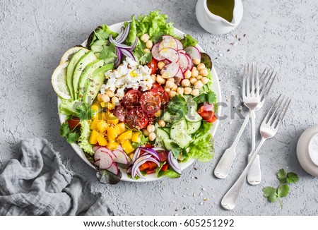 Spring vegetable salad with chickpeas, avocado and feta. Tasty healthy food. Buddha bowl. On a gray background, top view    