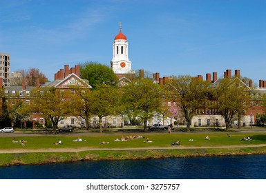 Spring View Of Harvard University Students Relaxing On Grass Between Charles River And Dunster House, In Cambridge, Massachusetts.