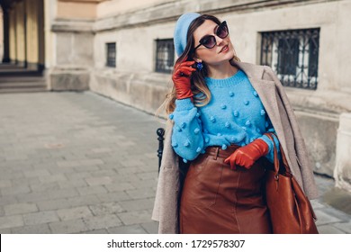 Spring vintage retro fashion female accessories and clothes. Woman wearing sweater beret leather skirt purse on street.