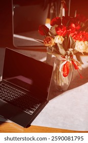 Spring work setting with a laptop and vibrant tulips in sunlit workspace
