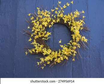 A Spring Wreath Of Yellow Forsythia On A Blue Door.