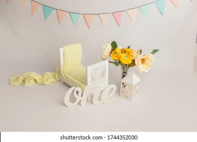 Spring yellow flowers next to baby bed with decor in white baby's room, copy space concept. Stylish baby bed near light wall in interior of children's room. Bucket of flowers. wooden One.