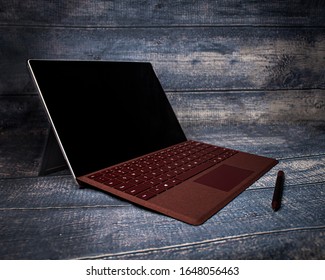 Springfield, IL / USA - February 2020: Microsoft's Surface Pro 6 All In One Tablet And Laptop With Maroon Detachable Keyboard And Matching Maroon Tablet Pen.  Showcased On A Wood Background.