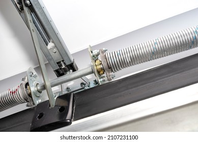 Springs tensioning the garage door mechanism, view from the inside, visible rail with chain and spring protection. - Shutterstock ID 2107231100