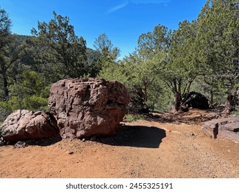 Springtime view of a large boulder beside the Gowan hiking trail in Tonto Natural Bridge State Park in Pine, Arizona with bright blue sky copy space in an area above the natural bridge.