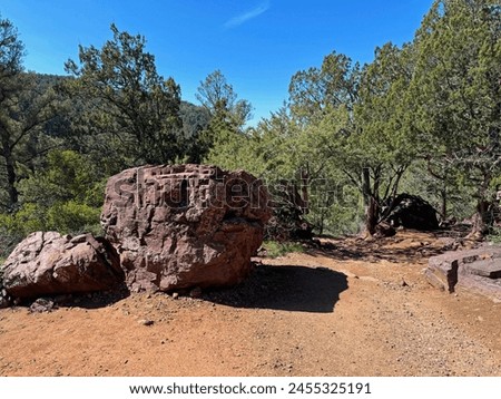 Springtime view of a large boulder beside the Gowan hiking trail in Tonto Natural Bridge State Park in Pine, Arizona with bright blue sky copy space in an area above the natural bridge.