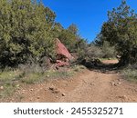 Springtime view of a large red rock beside the Gowan hiking trail in Tonto Natural Bridge State Park in Pine, Arizona with bright blue sky copy space in an area above the natural bridge.