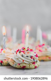 Sprinkle Birthday Cookies That Consist Of A Soft, Buttery Sprinkle Cookie That Is Topped With A Piped Cream Cheese Frosting And A Lit Birthday Candle. Close Up. 