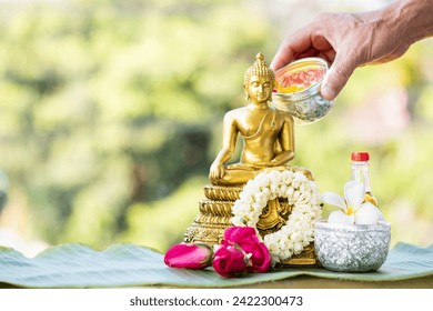 Sprinkle water onto buddha with water with flowers , thai traditional perfume and Jasmine garland to worship during the Thai Songkran festival.