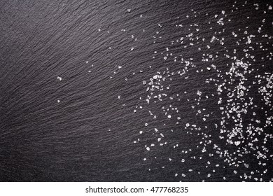 Sprinkled Sea Salt Over Black Slate Stone Background, Top View