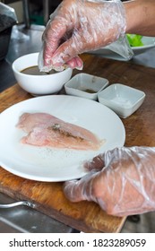 Sprinkling Salt And Pepper To Raw Chicken Breast At The Kitchen. Hands With Clear Plastic Gloves For Hygiene Purposes.