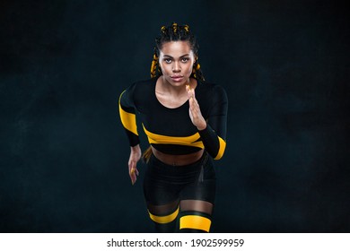 Sprinter run. Strong athletic woman running on black background wearing in the sportswear. Fitness and sport motivation. Runner concept.