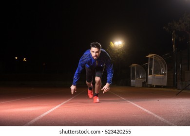 Sprinter, Sprinting, Start Position. Running Track, Night, Dark.