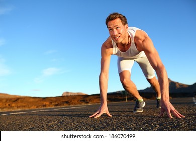 Sprinter starting sprint - man running getting ready to start sprinting run. Fit male runner athlete training outside on road in beautiful mountain landscape nature. - Shutterstock ID 186070499