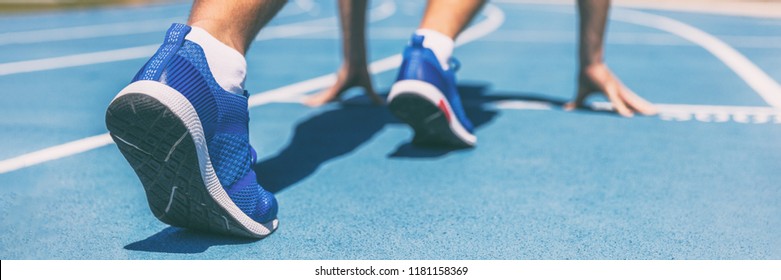 Sprinter waiting for start of race on running tracks at outdoor stadium. Sport and fitness runner man athlete on blue run track with running shoes. Banner panorama.