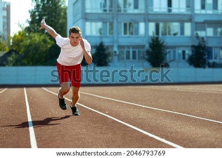Sprinter. Young Caucasian sportive man, male athlete, runner practicing alone at public stadium, sport court or running track outdoors. Concept of healthy active lifestyle, motion, hobby.