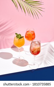 Spritz Cocktail Set On White Table. Tropical Palm Leaf Shadow. Summer Cocktail Group. Pink And Classic Blue Background