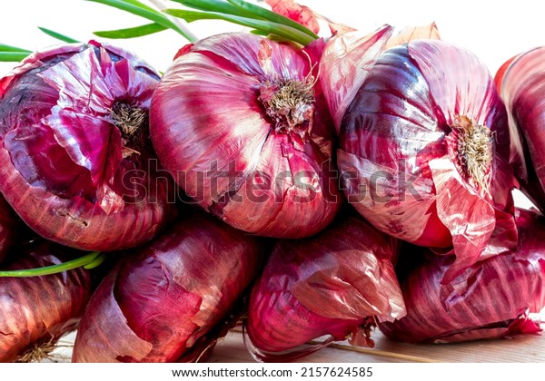 Sprouted\
onion of red dessert sweet onion. Sweet dessert red onion, flat\
shape. Onion has sprouted, young green feathers are visible. Topic\
- healthy and simple food, rich in\
vegetables