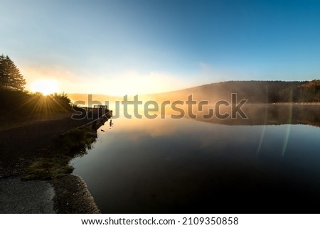 Spruce Knob lake blue sky water in West Virginia mountains fall autumn fog mist sunrise morning glowing yellow sunlight sun flare rays beams in Monongahela National Forest