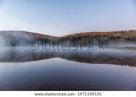 Spruce Knob Lake in West Virginia at sunrise with nobody and landscape view of blue water and forest trees in autumn fall season