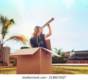 I spy with my little eye. Shot of a cute little girl in a pirate costume playing in a cardboard box in her backyard. - Powered by Shutterstock